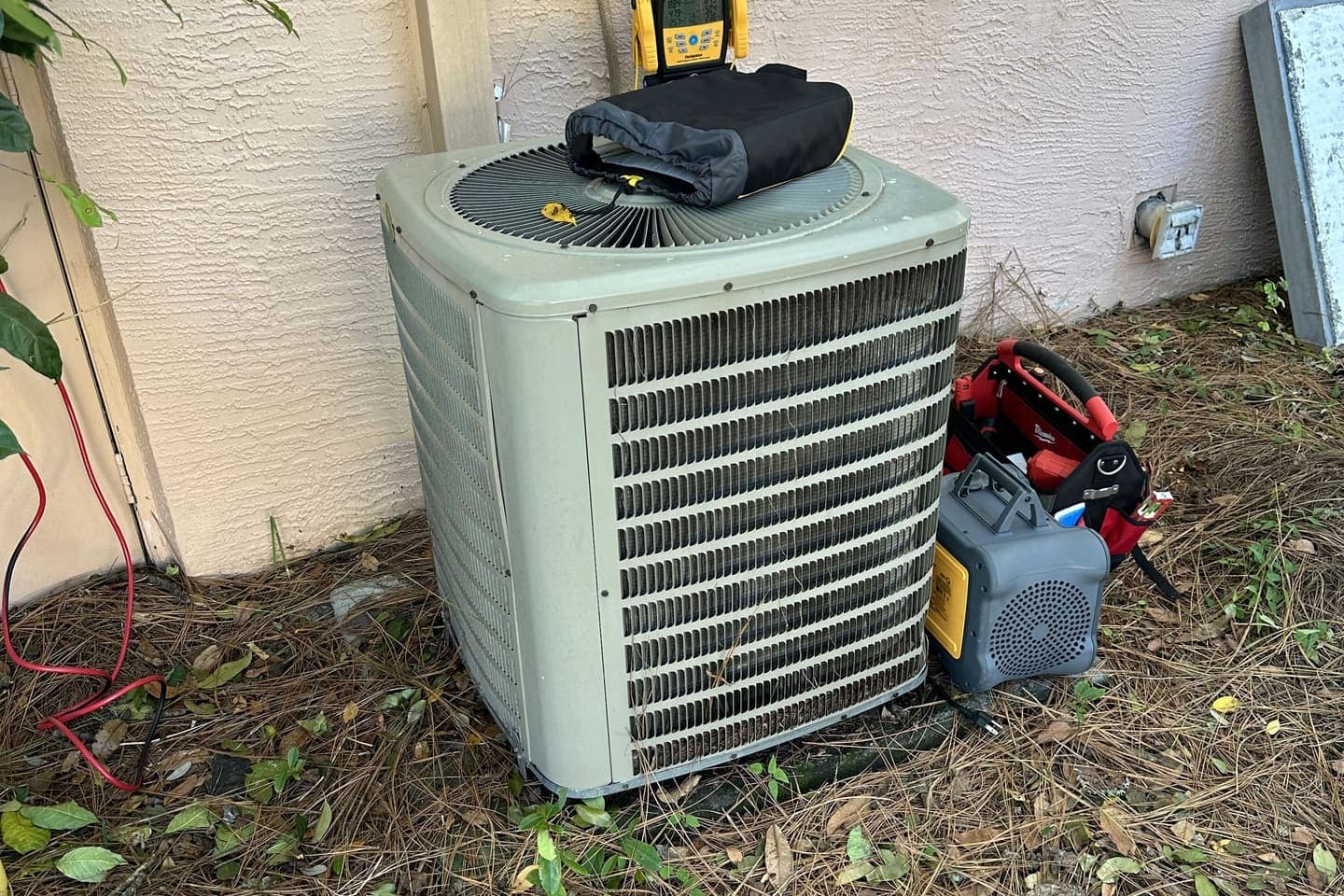 A green outdoor condenser with a vacuum pump and gauge tools beside it in Spring Hill, FL.