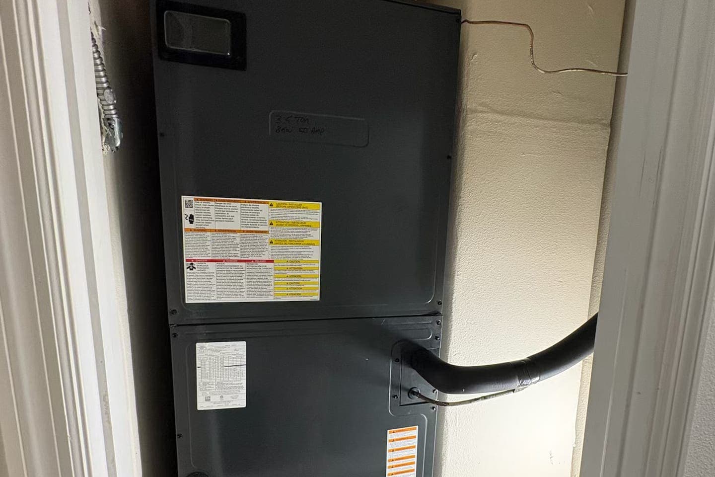 A black air handler cabinet with its drain line.