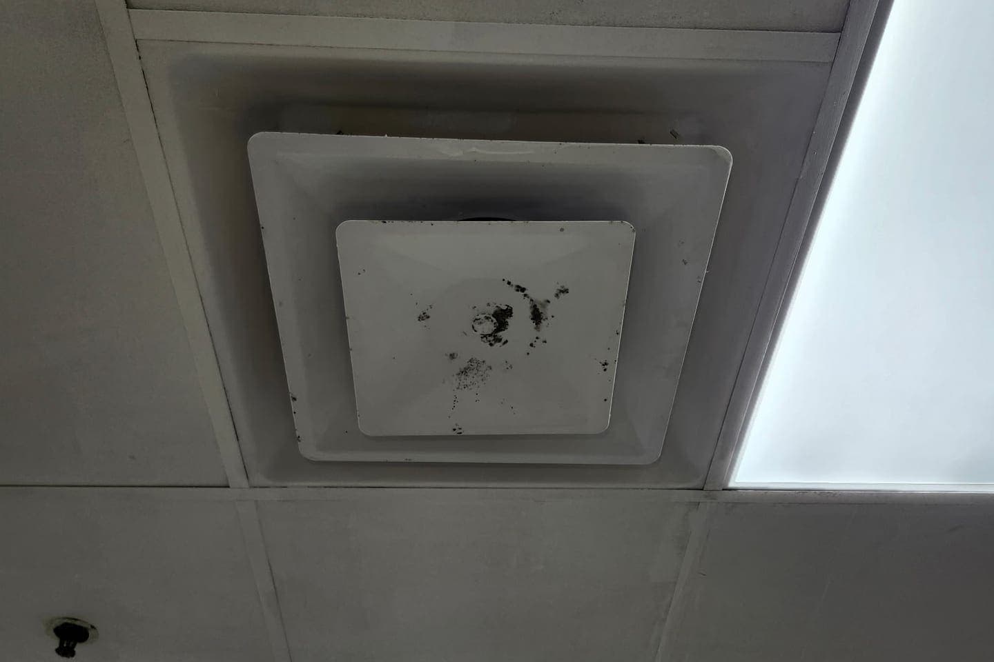 A ceiling supply vent with dust stains around it.