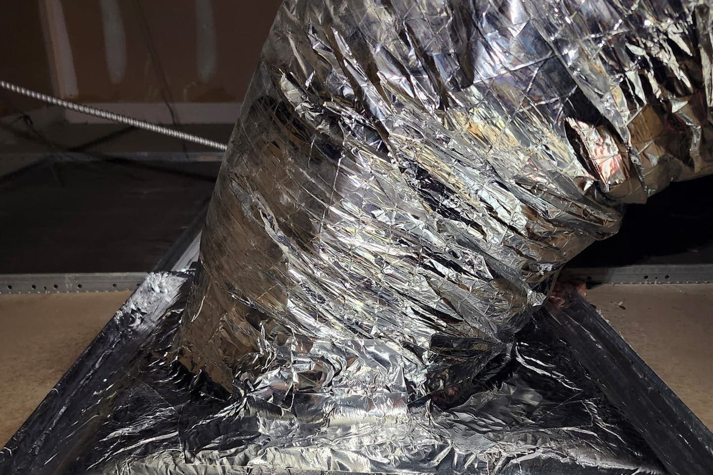 A flexible duct connection sealed with foil tape.
