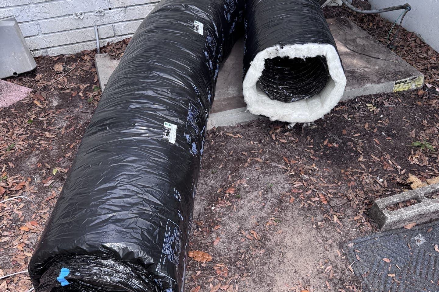 New insulated flex duct lying beside a house, ready to install in Hernando County, FL.
