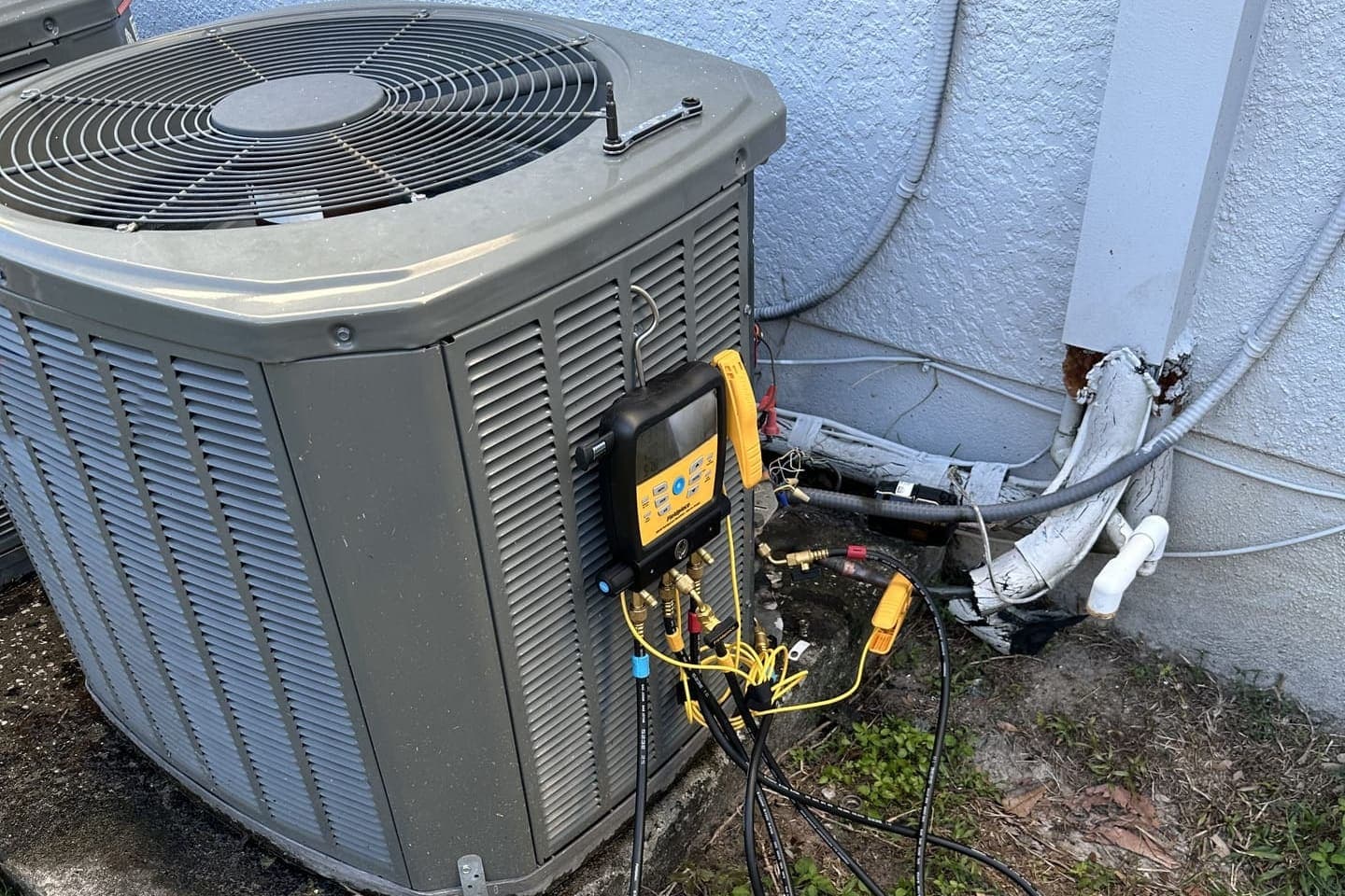 An outdoor condenser with gauge hoses and a recovery setup connected in Spring Hill, FL.