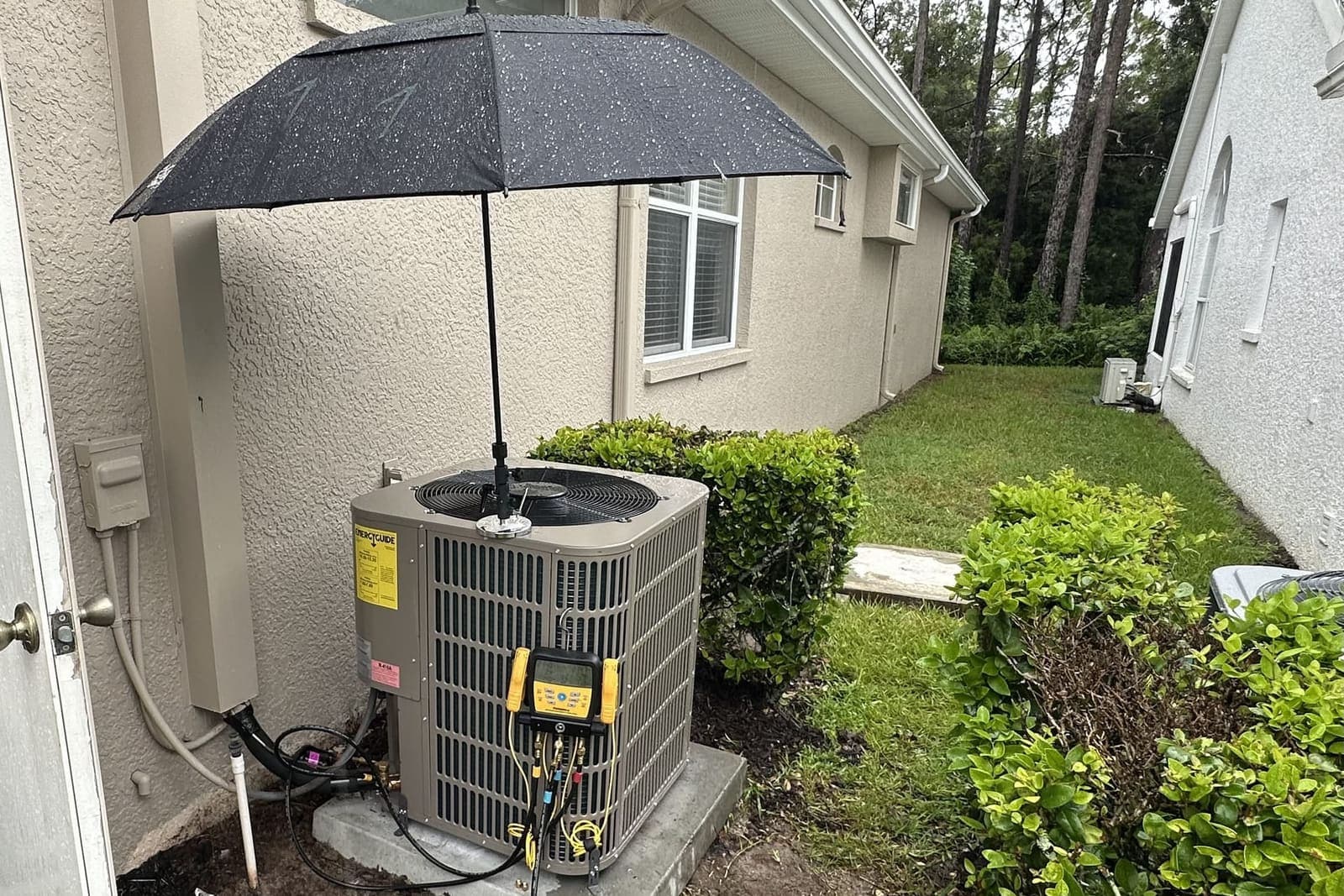An outdoor condenser shaded by an umbrella while gauges are connected in Hernando County, FL.