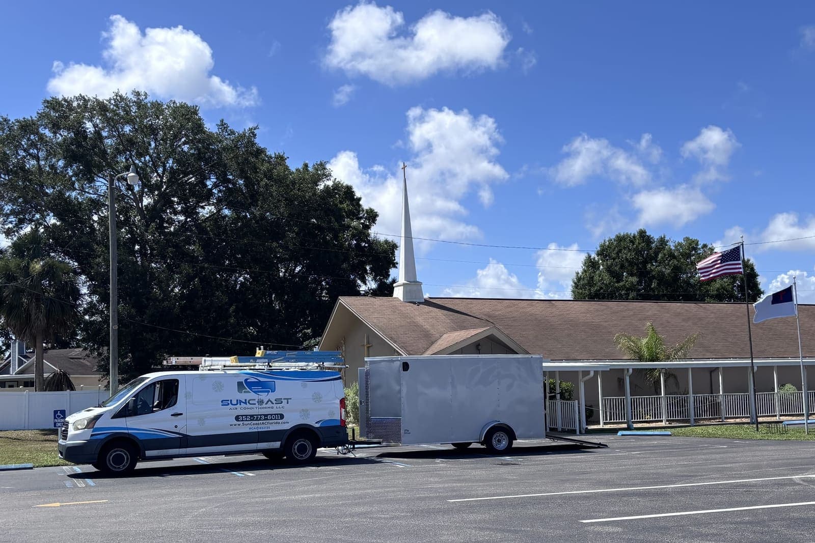 The SunCoast van and work trailer parked in a church lot in Hudson, FL.
