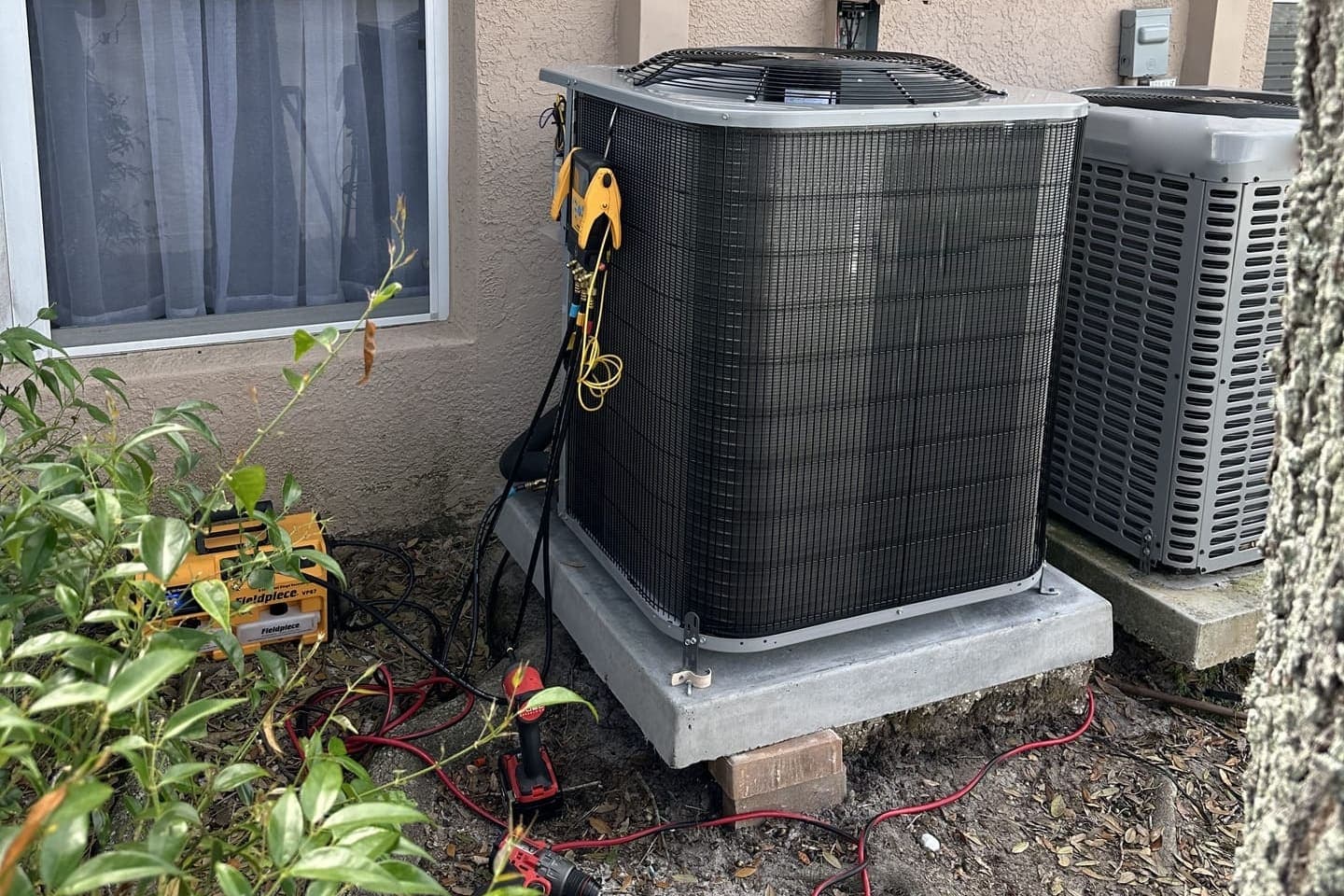 Two outdoor condensers side by side with gauges connected in Pasco County, FL.