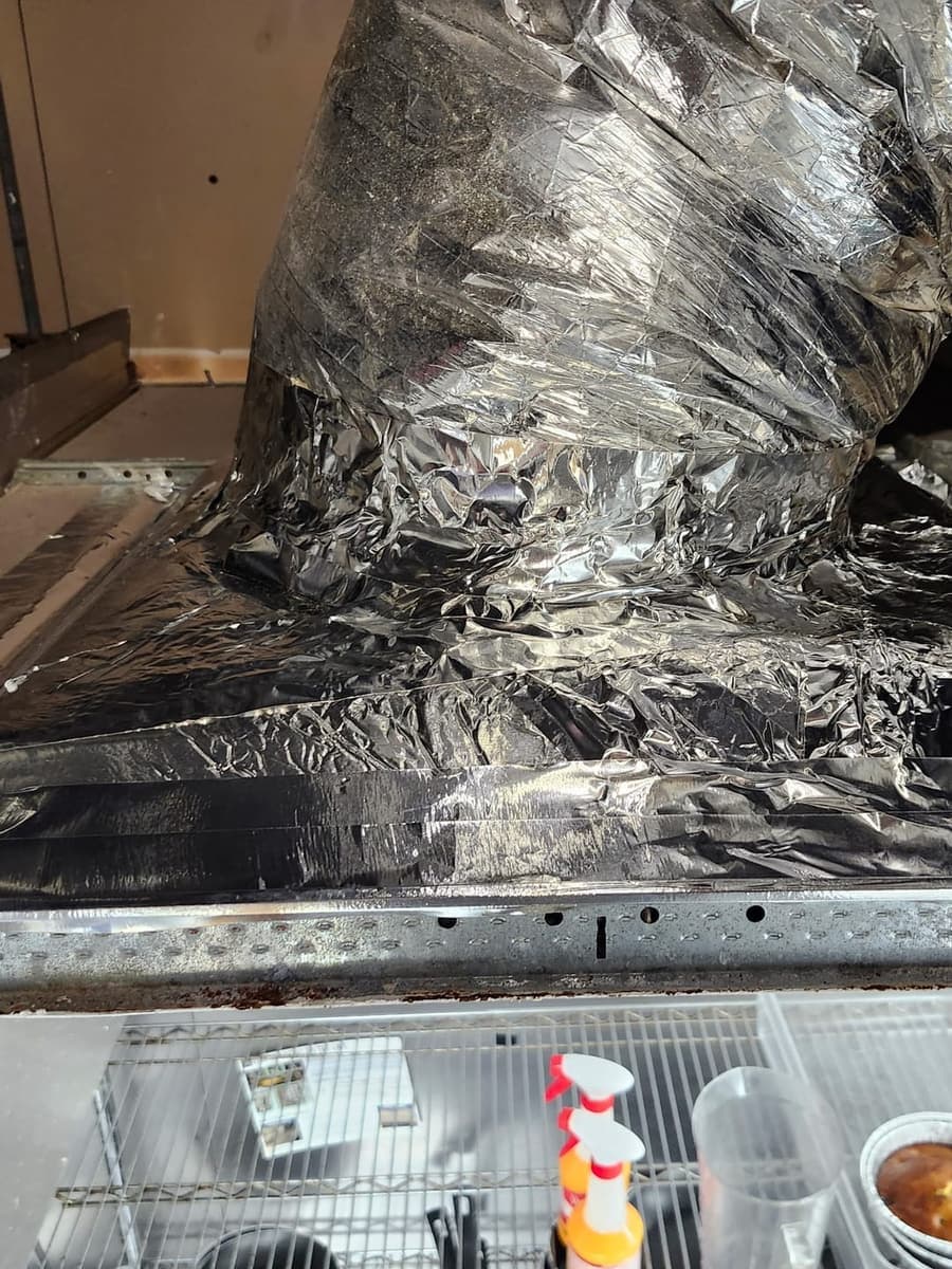 A flexible duct and plenum wrapped in foil tape.