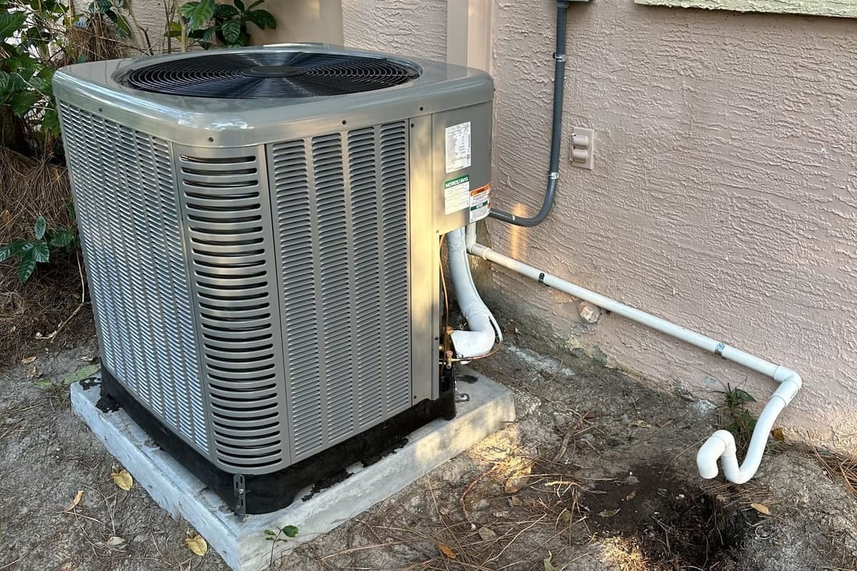 A gray outdoor condenser on a composite pad beside a condensate drain line in Spring Hill, FL.