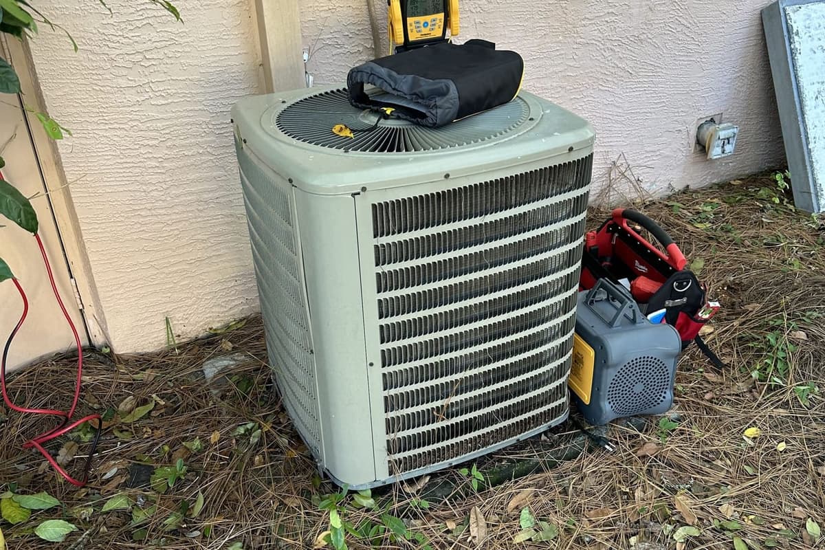 A green outdoor condenser with a vacuum pump and gauge tools beside it in Spring Hill, FL.