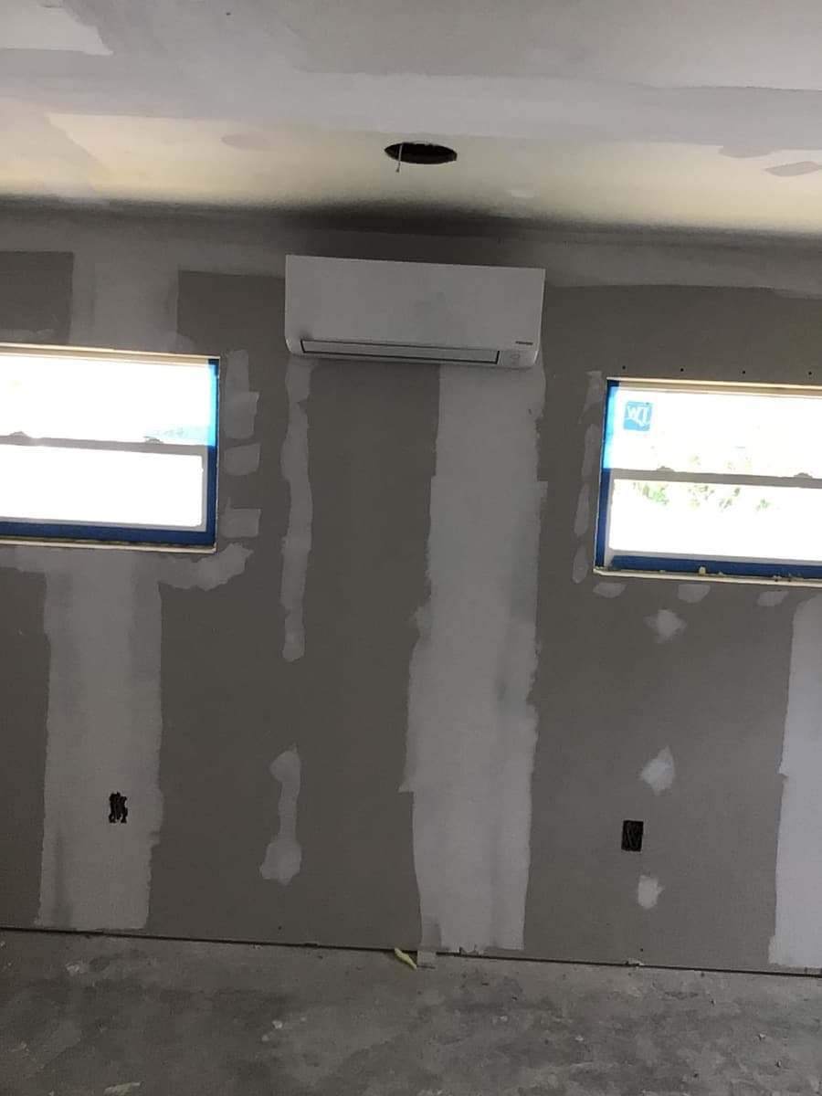 A mini-split indoor unit mounted high on a freshly patched wall.