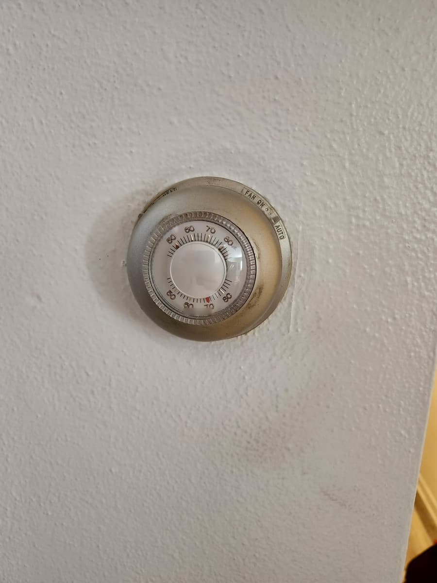 An old round dial wall thermostat.