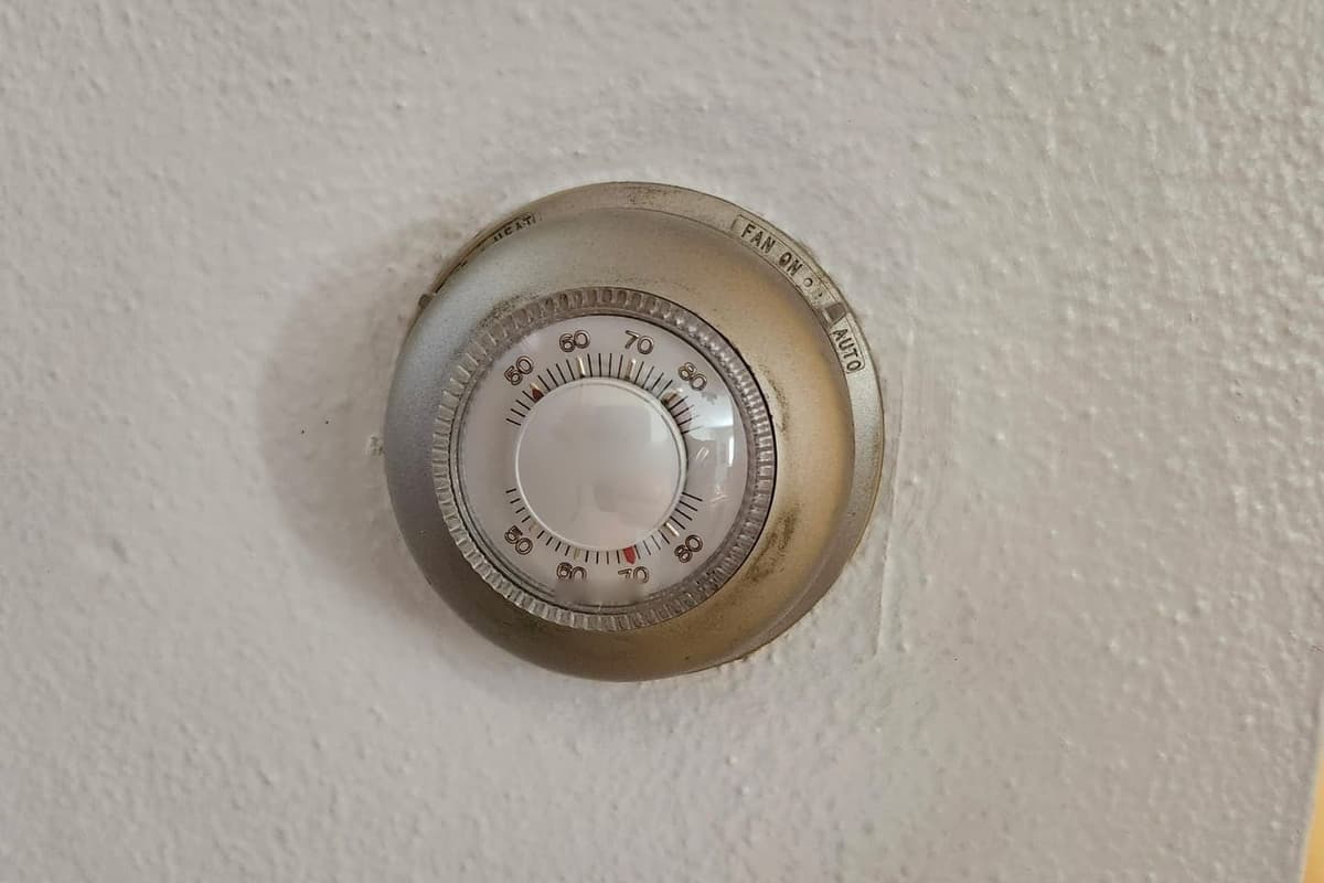 An old round dial wall thermostat.