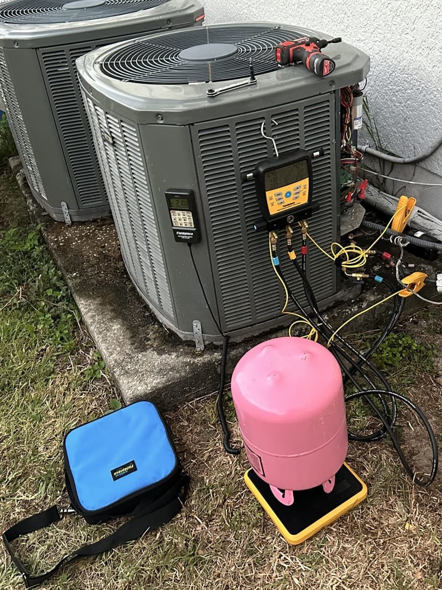 An outdoor condenser with a pink refrigerant cylinder and a recovery machine beside it in Spring Hill, FL.