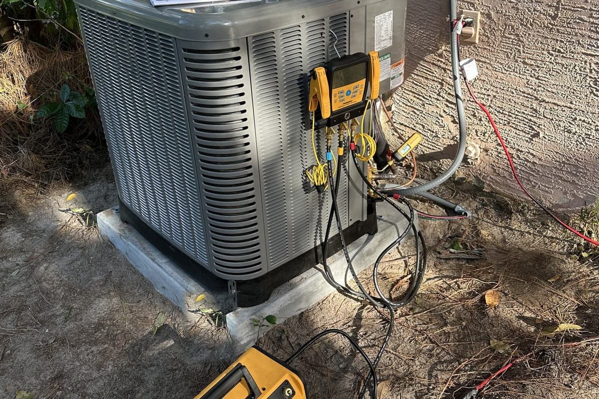 An outdoor condenser with yellow gauge hoses connected for a refrigerant check in Spring Hill, FL.