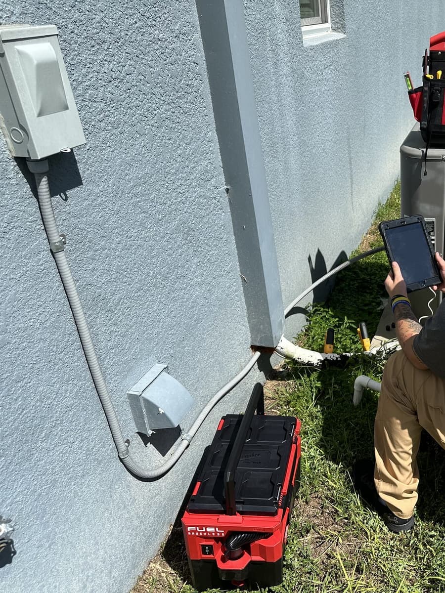 A SunCoast technician checking readings on a tablet beside an outdoor condenser in Spring Hill, FL.