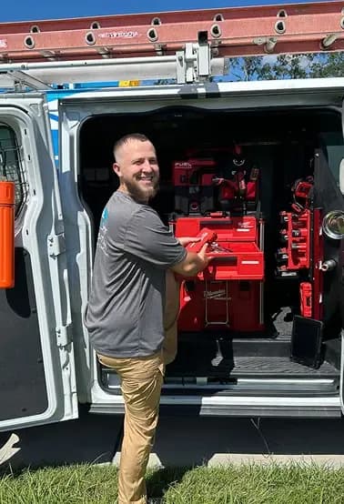 Smiling SunCoast AC technician taking tools from the organised tool racks inside the company van