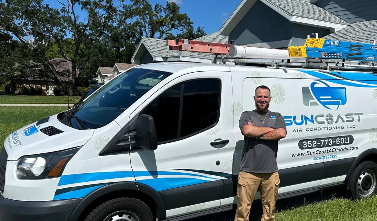 SunCoast Air Conditioning technician JJ standing beside the branded SunCoast AC service van outside a Florida home