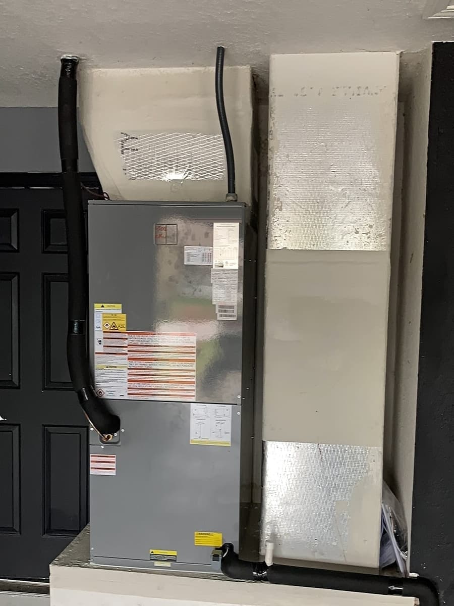 An air handler cabinet beside a dark door.