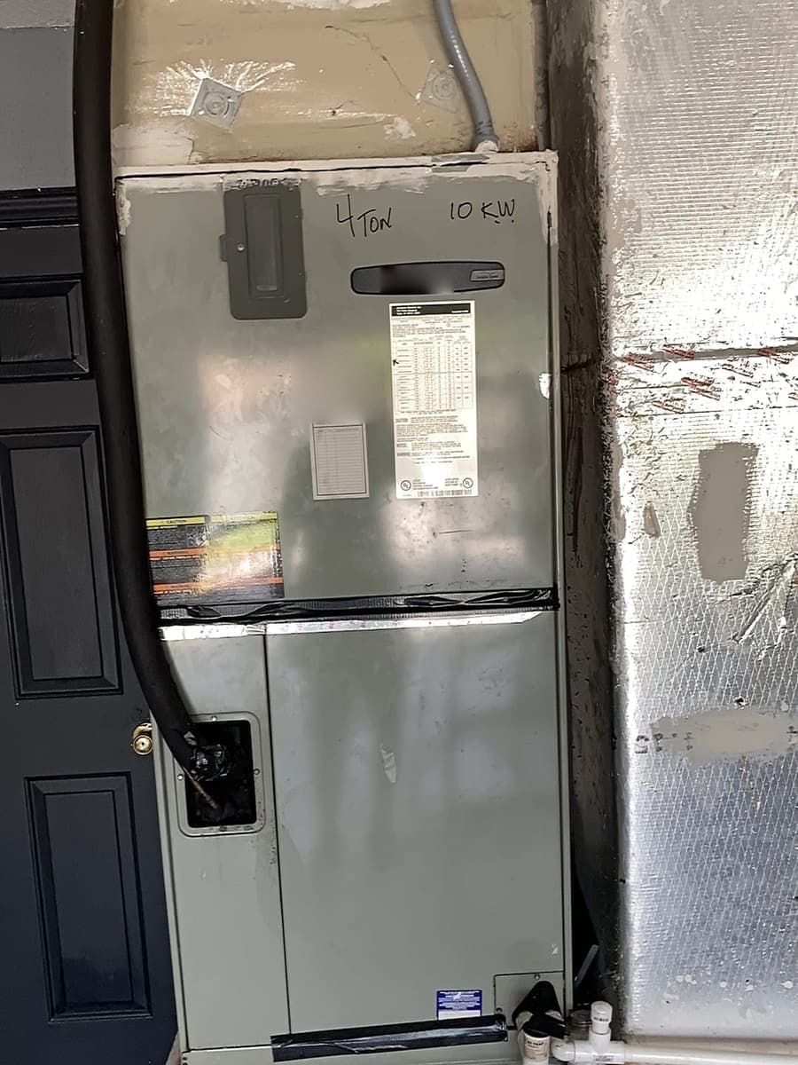 An air handler cabinet with a drain line running down its side.