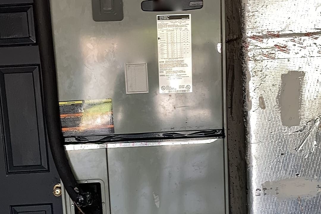 An air handler cabinet with a drain line running down its side.