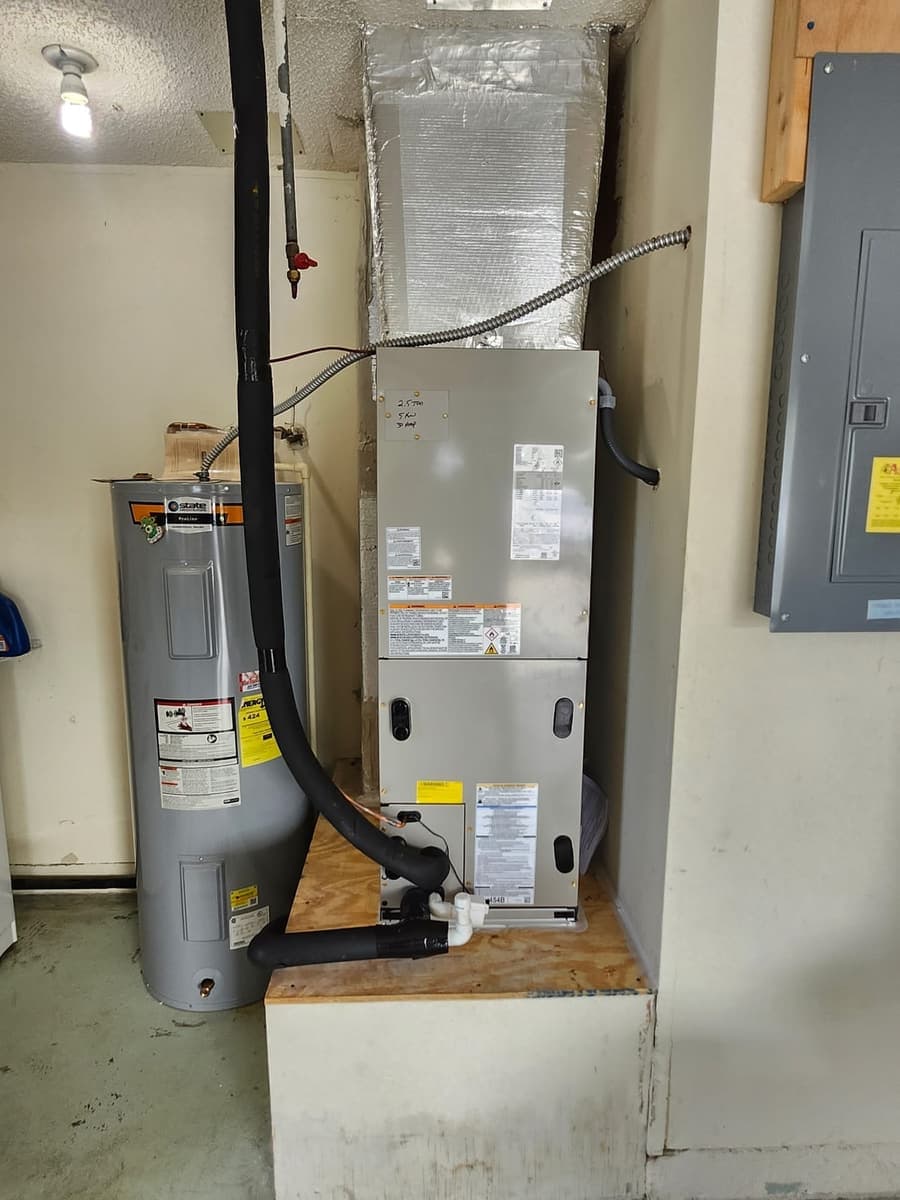 An air handler stacked above a water heater in a closet.