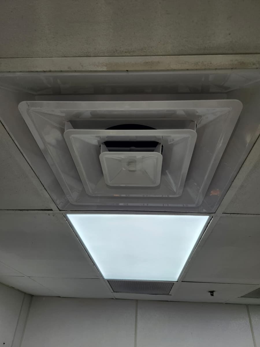 A ceiling return grille beside a light panel.