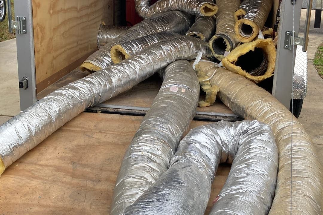 Coils of flexible duct stacked in the back of a work trailer.