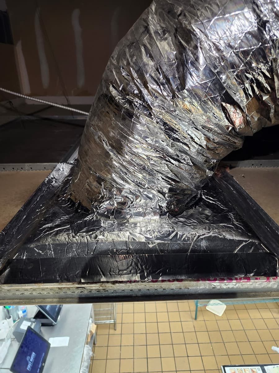 A flexible duct connection sealed with foil tape.