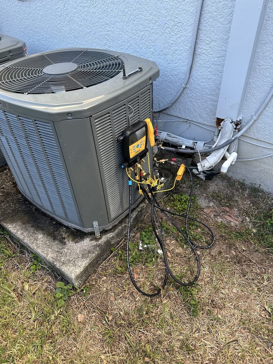 An outdoor condenser with gauge hoses and a recovery setup connected in Spring Hill, FL.