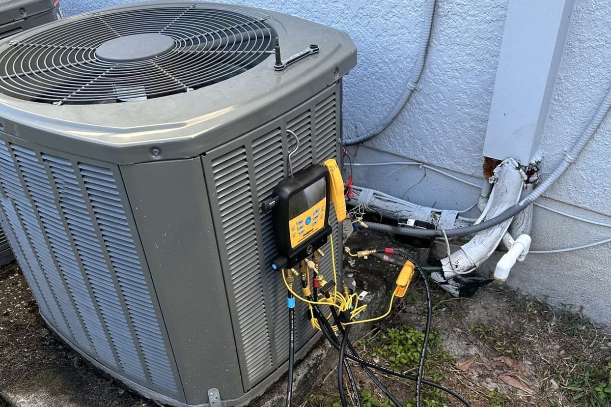 An outdoor condenser with gauge hoses and a recovery setup connected in Spring Hill, FL.