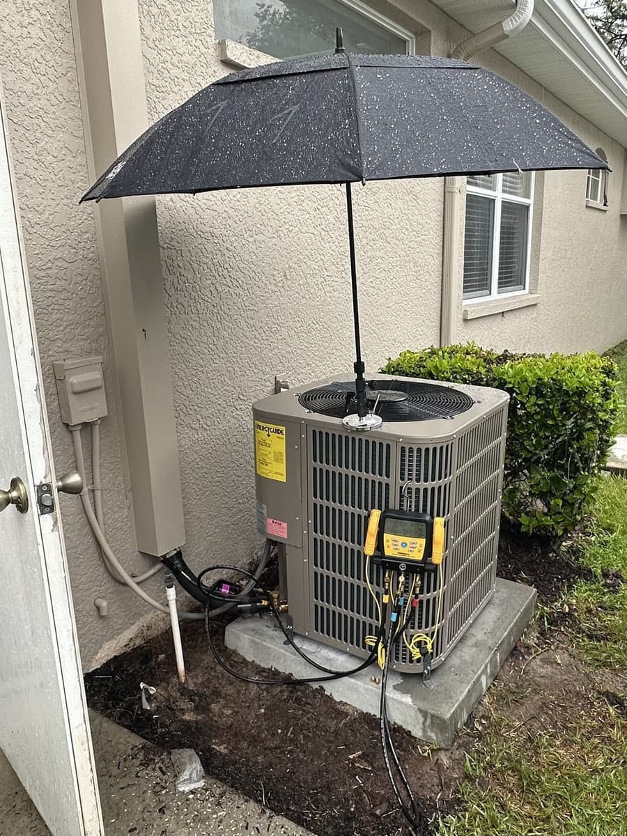 An outdoor condenser shaded by an umbrella while gauges are connected in Hernando County, FL.