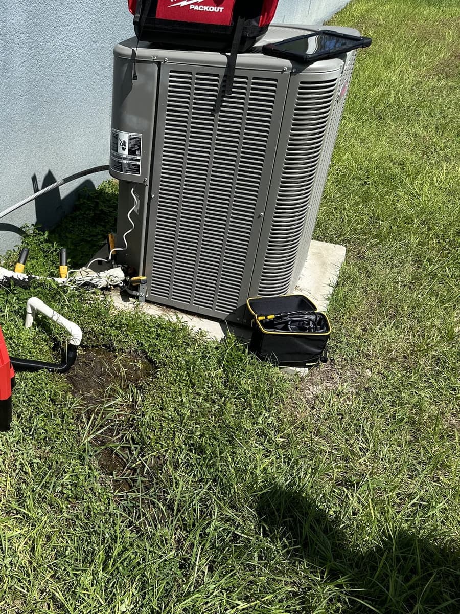 An outdoor condenser with tool cases and a test meter set out beside it in Spring Hill, FL.