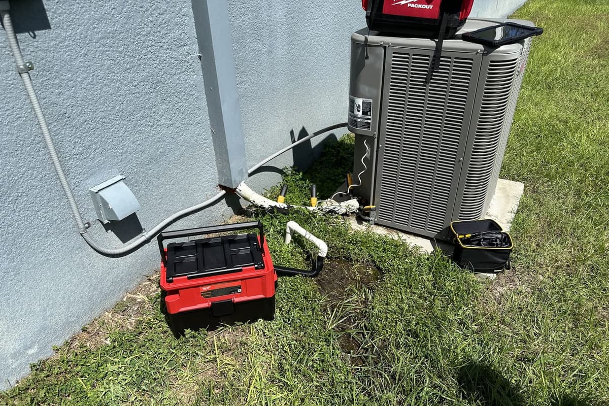 An outdoor condenser with tool cases and a test meter set out beside it in Spring Hill, FL.