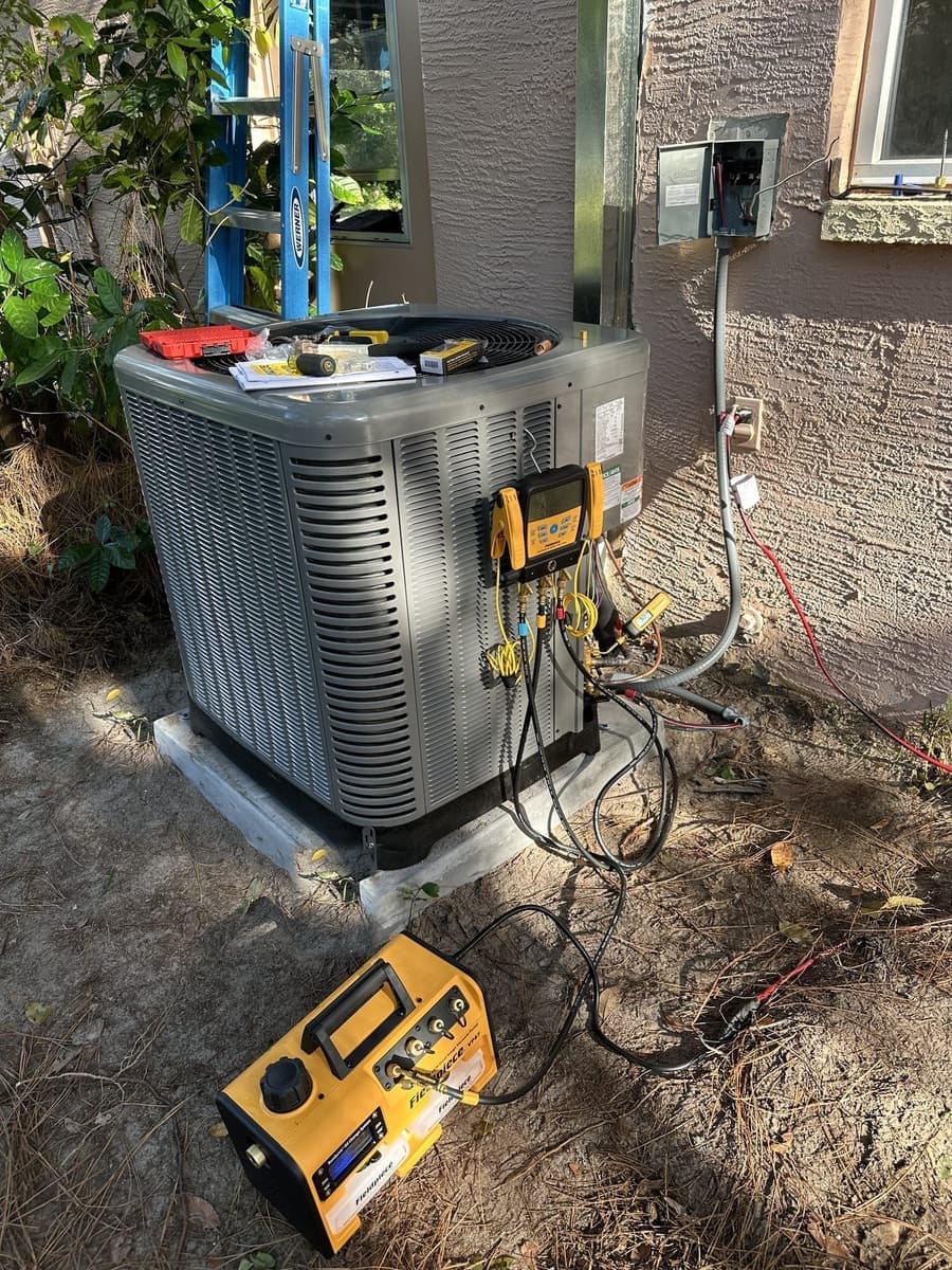 An outdoor condenser with yellow gauge hoses connected for a refrigerant check in Spring Hill, FL.