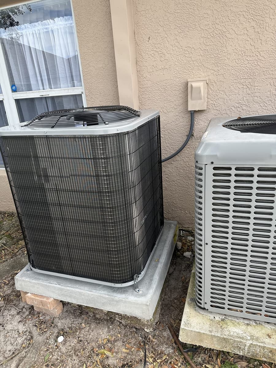 A pair of outdoor condensers beside a stucco wall in Pasco County, FL.