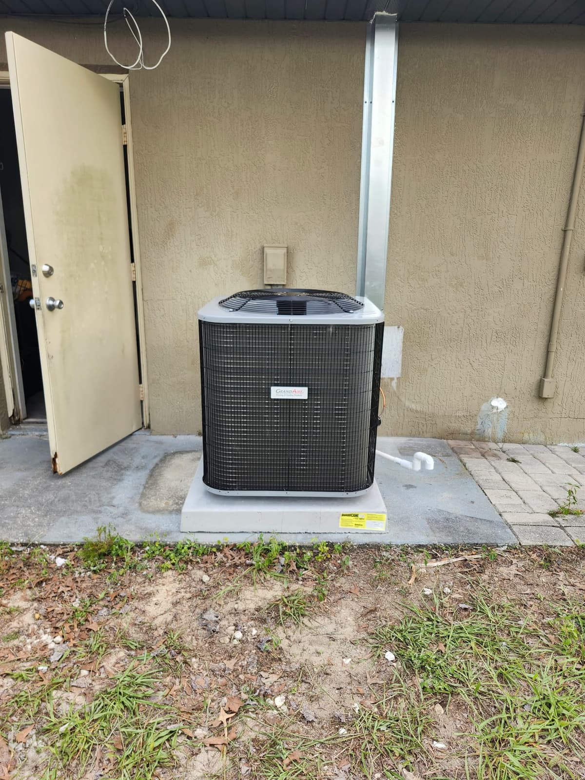 Outdoor GrandAire air conditioning condenser installed on a concrete pad beside a Florida home