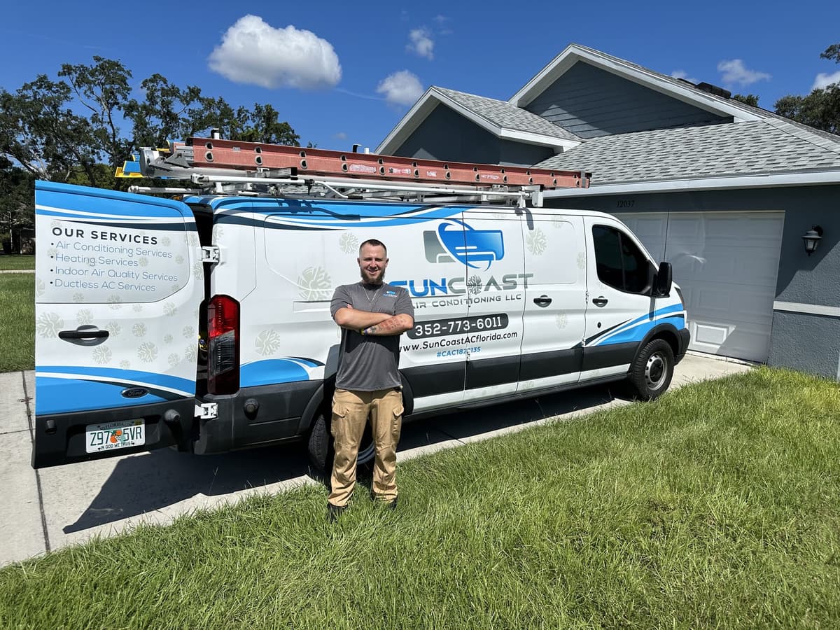 SunCoast Air Conditioning technician standing beside the service van in a customer's driveway