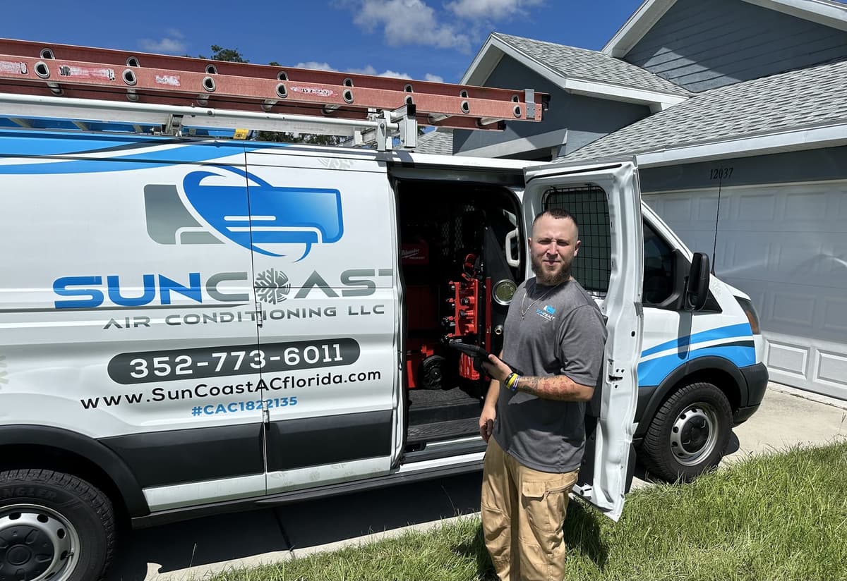 SunCoast Air Conditioning technician holding a diagnostic tool beside the open service van