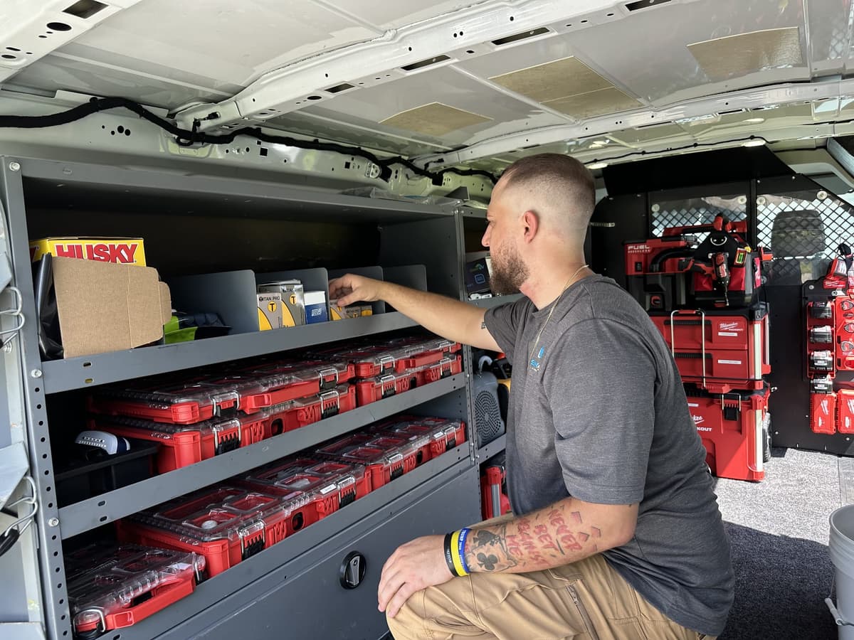SunCoast technician reaching for parts stocked on shelving inside the service van