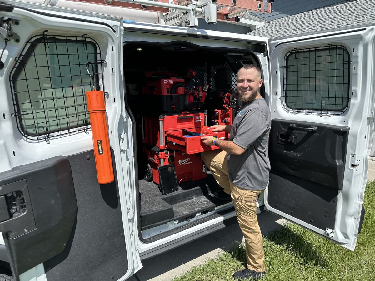 SunCoast technician selecting tools from the organised racks inside the open rear doors of the service van