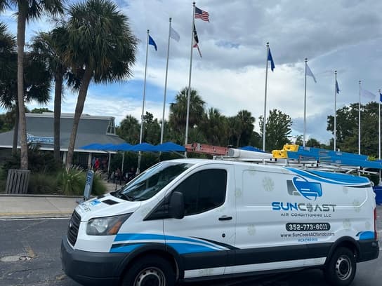 SunCoast Air Conditioning van parked beneath a row of flagpoles in Weeki Wachee, Florida