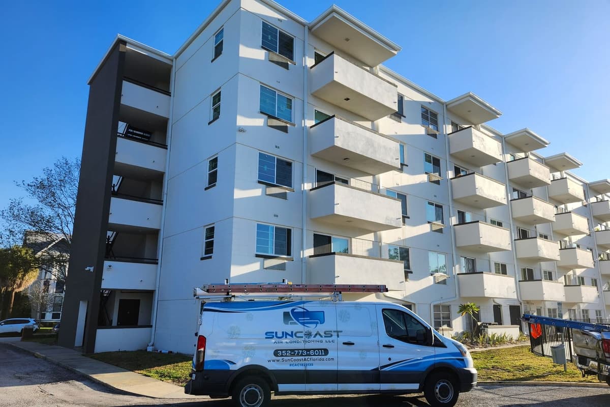 The SunCoast Air Conditioning van parked outside a mid-rise apartment building.