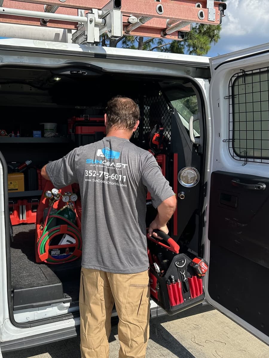 A SunCoast technician at the open back doors of the van, with tool cases racked inside in Spring Hill, FL.