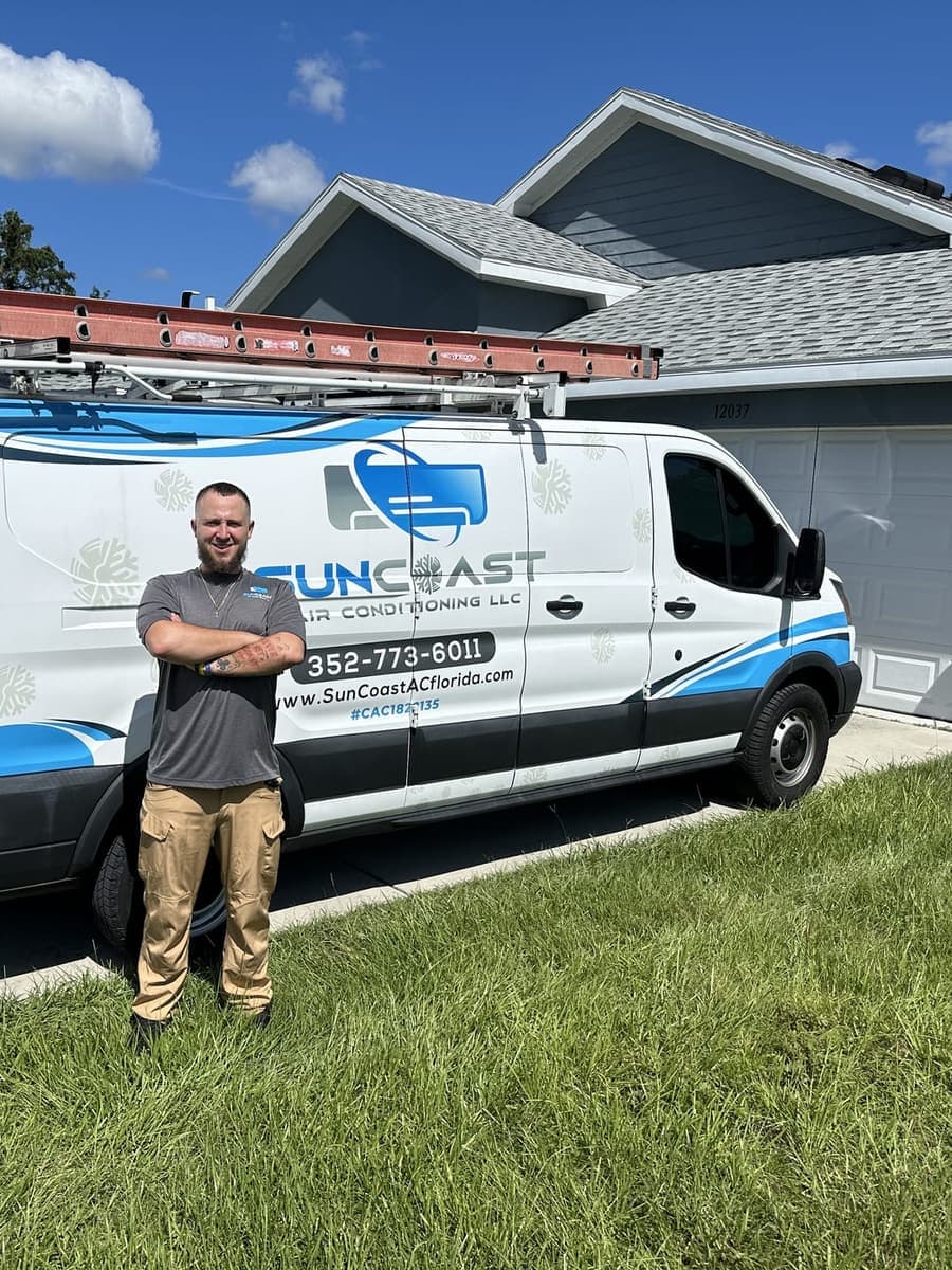 A SunCoast technician posing beside the service van in a driveway in Spring Hill, FL.