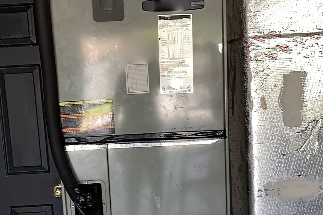 An air handler cabinet with a drain line running down its side.
