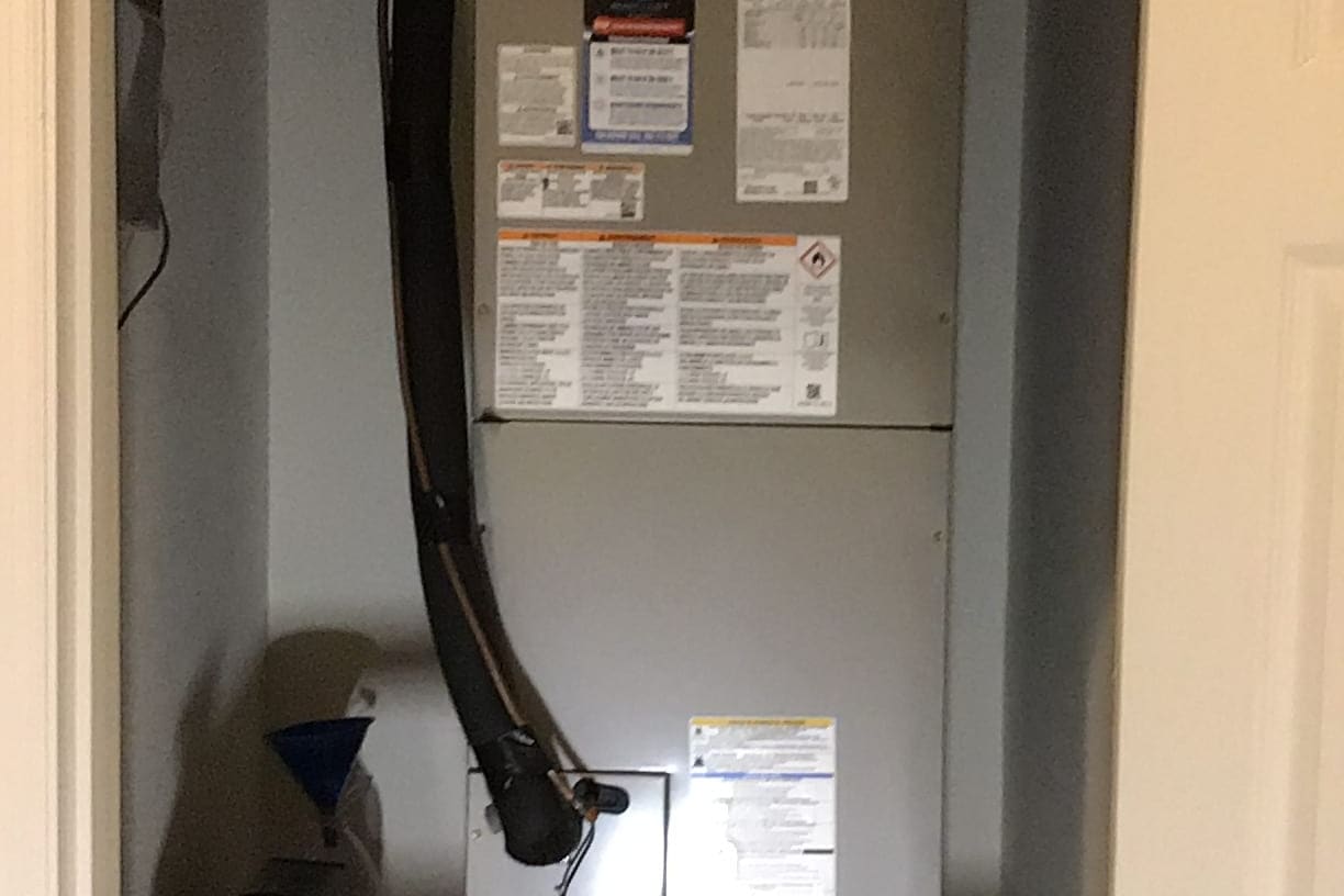 An air handler with its condensate drain and shut-off labels.