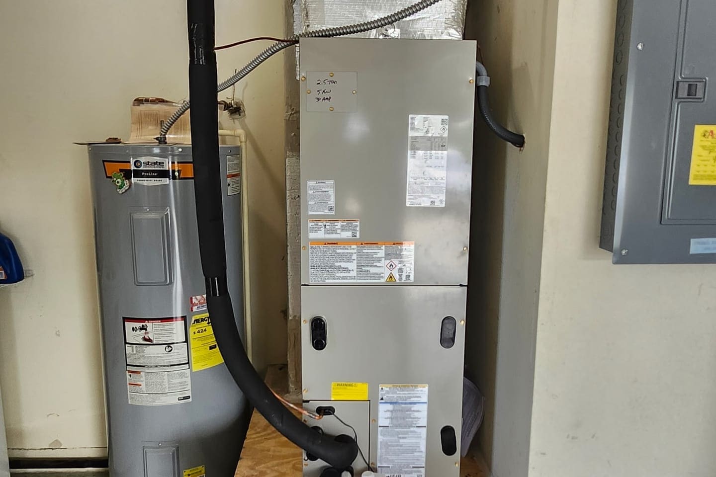 An air handler stacked above a water heater in a closet.