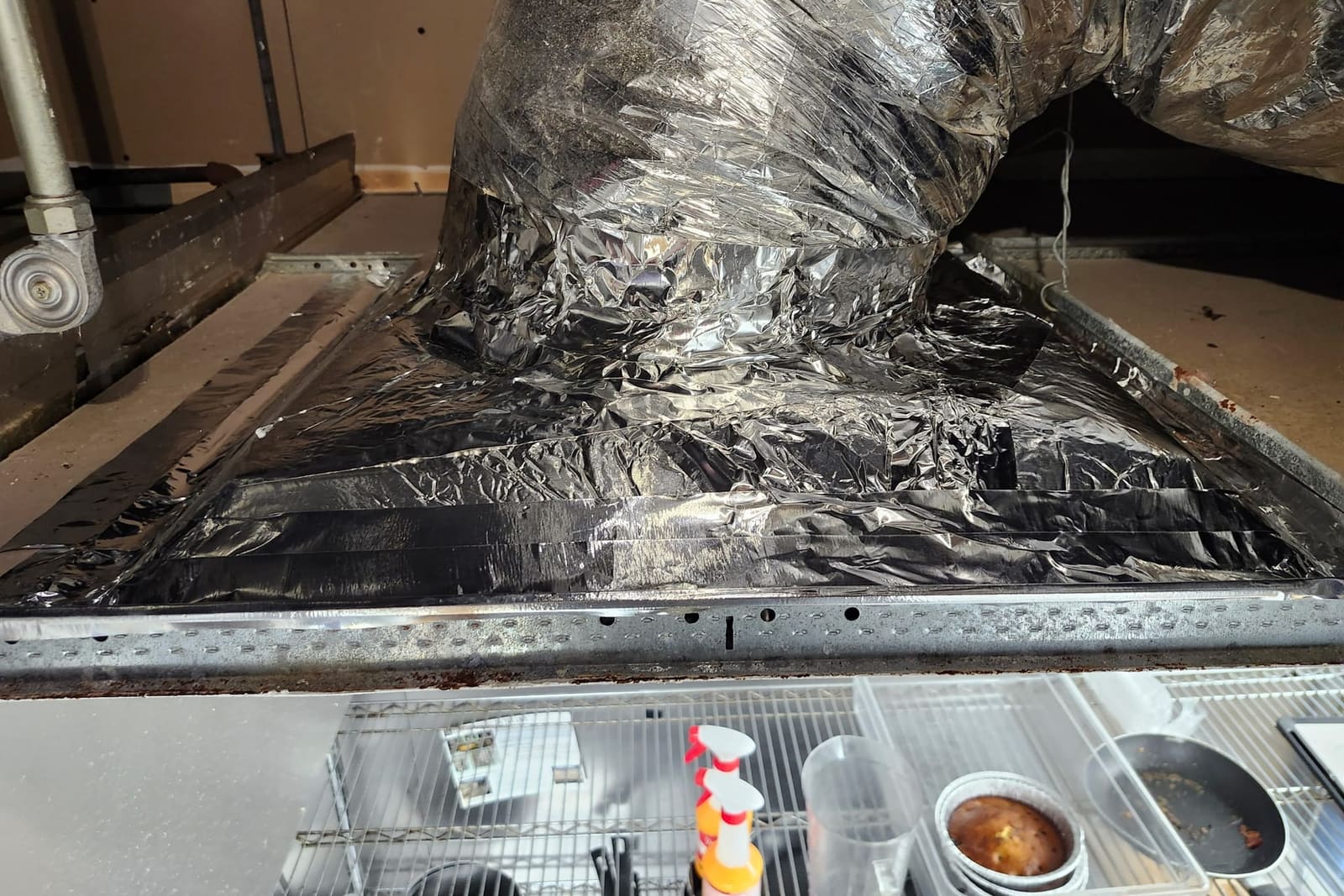 A flexible duct and plenum wrapped in foil tape.