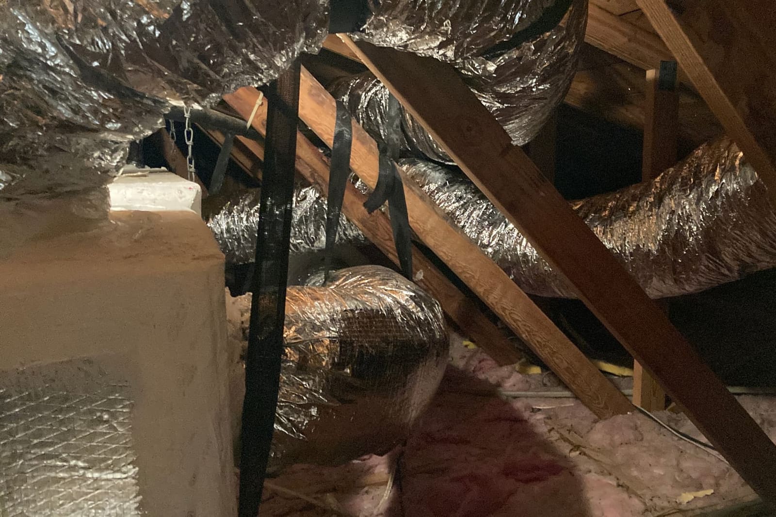 Flexible duct runs crossing attic rafters.