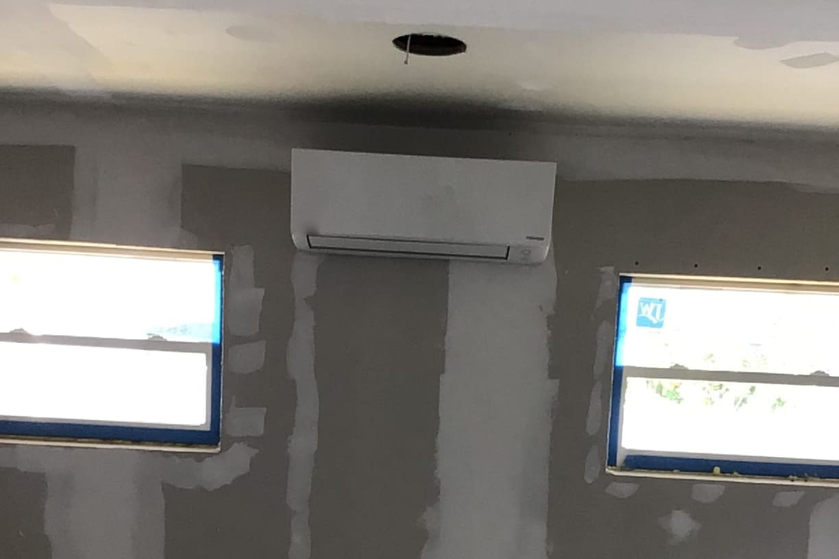 A mini-split indoor unit mounted high on a freshly patched wall.