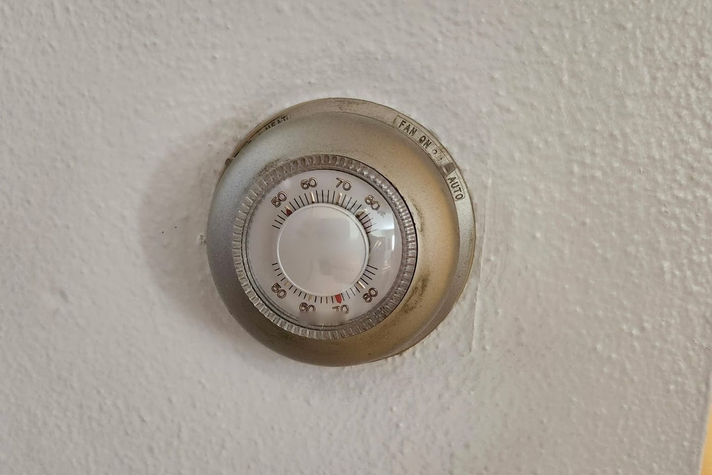 An old round dial wall thermostat.